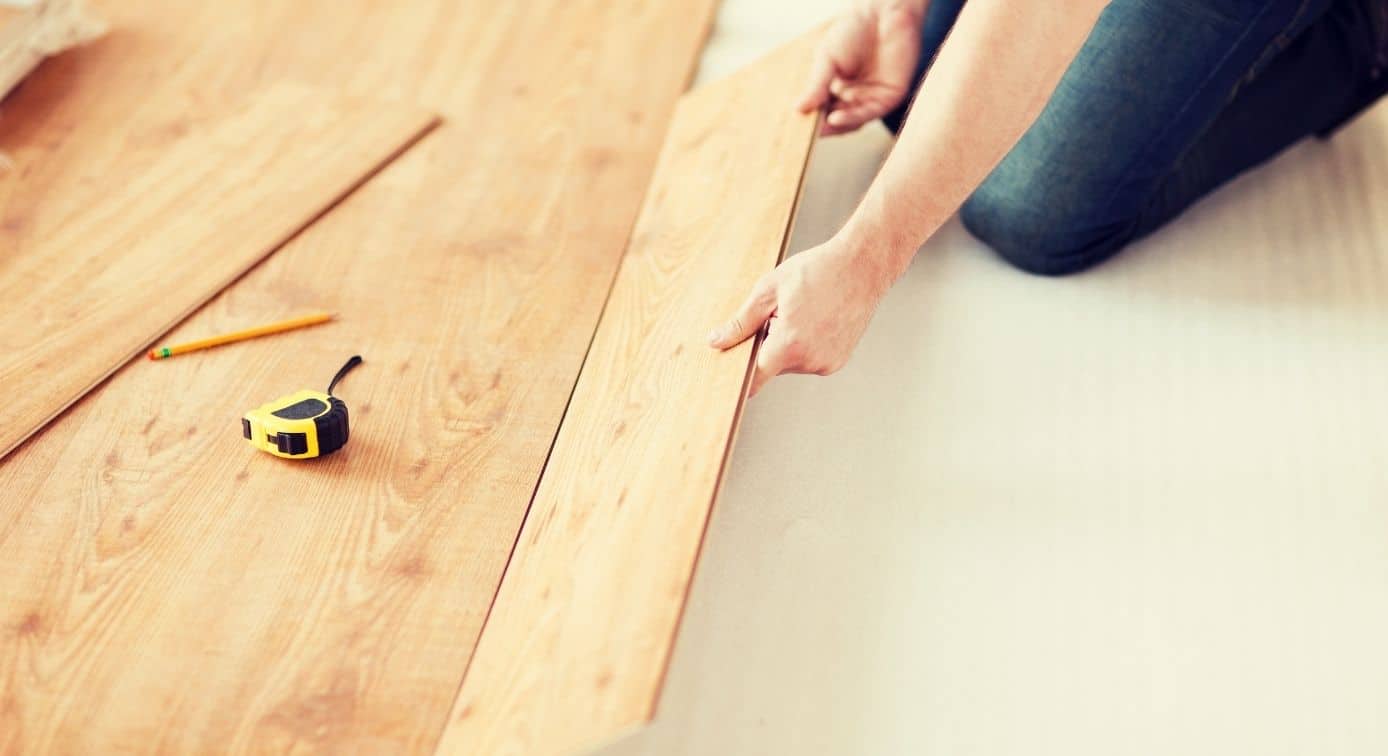 a person on their hands and knees installing LVP flooring