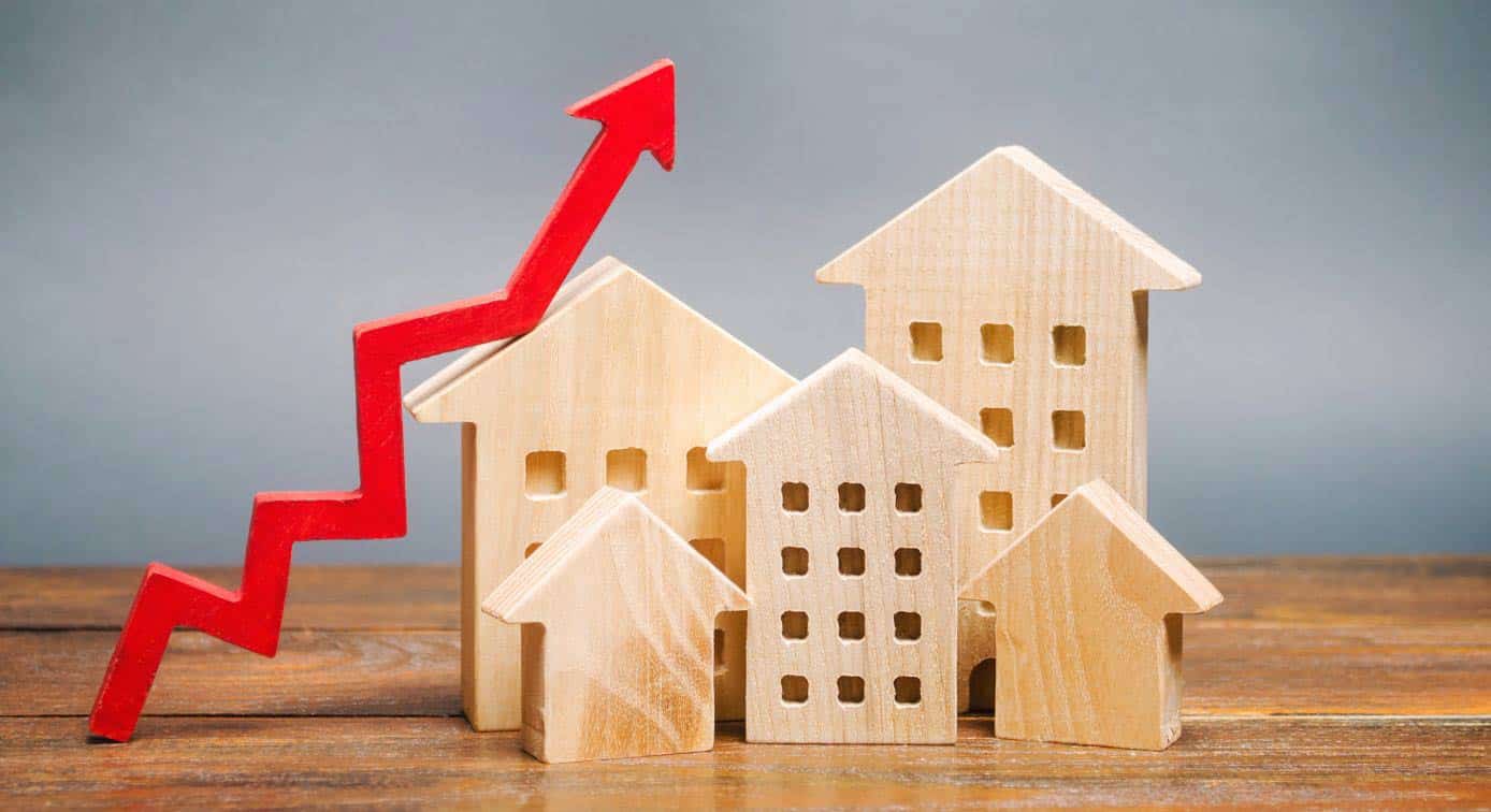 small wooden models of houses with a growth factor arrow beside them